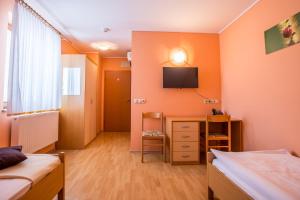 a bedroom with two beds and a television on the wall at Guesthouse Beno in Starše