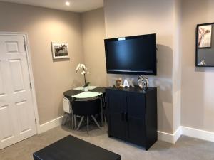 a room with a tv on a wall with a table at Eclipse Apartment No 1 in Newmarket