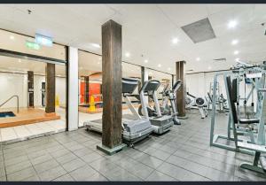 a gym with treadmills and machines in a room at Apartment Harborside Comfort in Sydney