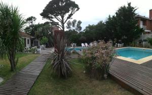 un patio trasero con piscina y terraza de madera en Hotel Solyma en Santa Teresita