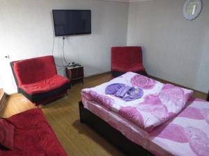 a room with two beds and two chairs and a tv at Lana Apartment in Tbilisi City