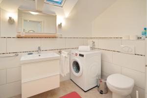 een witte badkamer met een wasmachine en een wastafel bij Rotspitz in Sonthofen +8 foto's