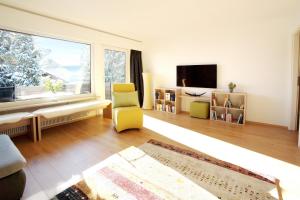 een woonkamer met een gele stoel en een groot raam bij Rotspitz in Sonthofen