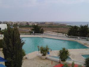 een groot zwembad met uitzicht op de oceaan bij Ikaria Village Apt 201 in Paphos City