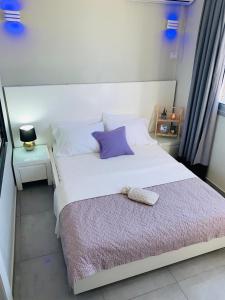 a bedroom with a white bed with a purple pillow at Motel Hofim in Bat Yam