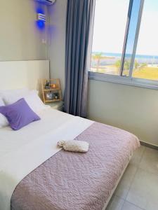 um quarto com uma cama com uma almofada e uma janela em Motel Hofim em Bat Yam