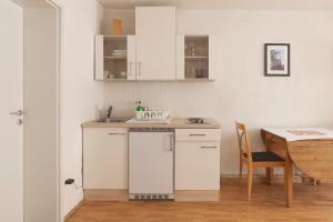 a white kitchen with a sink and a table at StayInn Apartments City Center in Freiburg im Breisgau