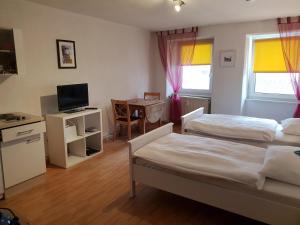 a room with two beds and a desk with a television at StayInn Apartments City Center in Freiburg im Breisgau