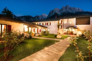 a house with a garden with mountains in the background at Bayern Resort Hotel - Adults only - mit Zugspitzblick - Eibsee-Nähe - Wellnessbereich - Naturpool im Sommer in Grainau