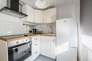 a kitchen with white cabinets and a refrigerator at Sunshine Apartment in Liepāja