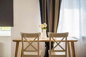 a table with two chairs and a vase with flowers on it at Sunshine Apartment in Liepāja