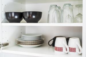 a shelf filled with plates and cups and bowls at Sunshine Apartment in Liepāja +3 photos