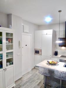 una cocina con armarios blancos y una mesa con un bol de fruta en Apartamento estilo nórdico en Malasaña (Madrid Centro), en Madrid