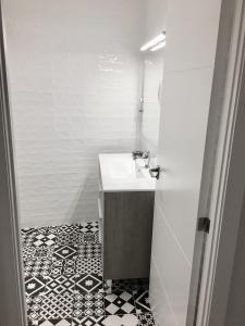 a bathroom with a sink and a black and white tile floor at Apartamento estilo nórdico en Malasaña (Madrid Centro) in Madrid