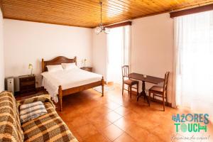 una camera da letto con un letto, un tavolo e un divano di Quinta de Sao Carlos ad Angra do Heroísmo