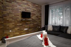 a living room with a couch and a brick wall at Liget Apartman in Gyula