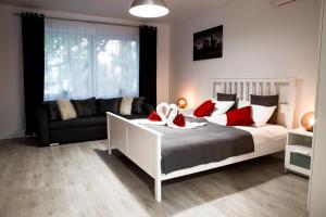 um quarto com uma cama branca e um sofá em Liget Apartman em Gyula