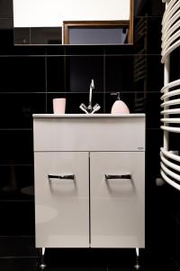 a white sink in a bathroom with a black wall at Liget Apartman in Gyula +18 photos