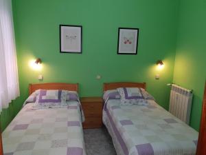 two beds in a room with green walls at Hostal Angelines in Madrid