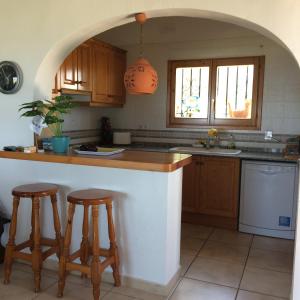 a kitchen with a counter and two bar stools at Villa Luz del Monte in Denia