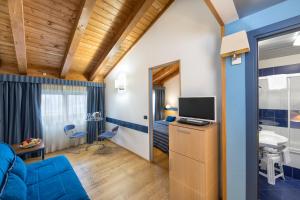 ein Wohnzimmer mit einem blauen Sofa und einem TV in der Unterkunft West Point Airport Hotel in Dossobuono
