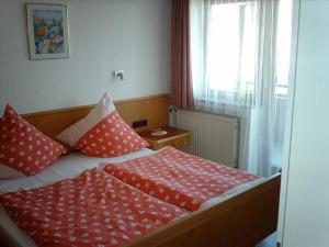 um quarto com uma cama com almofadas vermelhas e brancas em Haus Marianne em Oberjoch