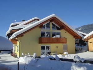 a house covered in snow with a balcony at Ferienwohnung Iselerblick in Bad Hindelang