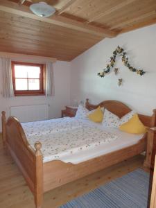 a bedroom with a large wooden bed with yellow pillows at Ferienhof Beim Kemptar in Bad Hindelang