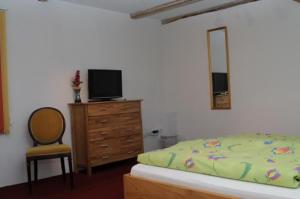 een slaapkamer met een bed en een dressoir met een televisie bij Green Mile Motel in Nideggen