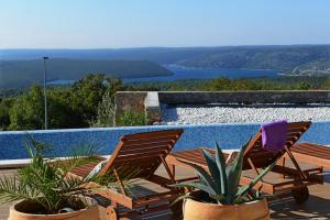 two chairs and a pool with a view of the water at Villa Olea in Koromačno