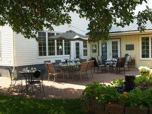 a patio with tables and chairs and an umbrella at Bakers Chest B&B in Truro
