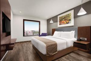 a hotel room with a large bed and a window at Howard Johnson by Wyndham, Kolkata Airport in Kolkata