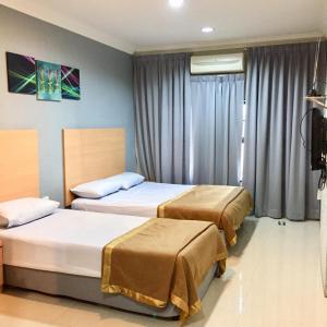 a hotel room with two beds and a window at Hotel Budget Lestari in Kota Bharu