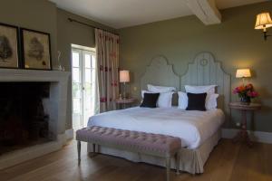 a bedroom with a large white bed and a fireplace at La Maison des Vignes - Domaine de la Soucherie in Beaulieu-sur-Layon