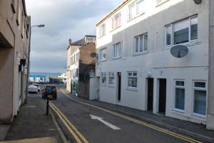 a car driving down a street next to a white building at Gallowgate Square Apartments in Largs