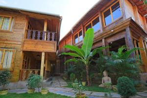 uma casa de madeira com uma estátua em frente em Brushwood Villa Resort em Palolem