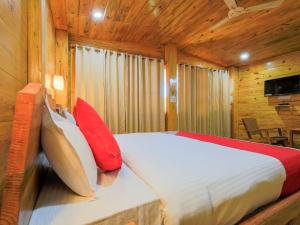 a bedroom with a bed with red and white pillows at Brushwood Villa Resort in Palolem