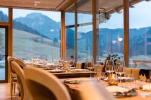 a dining room with tables and chairs and windows at Boutique hotel Vila Planinka in Zgornje Jezersko