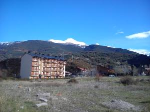 a building in a field with mountains in the background at La Casita del Pirineo in Villanúa