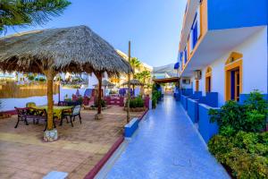 a patio with tables and chairs and a straw umbrella at Eltina Apartments in Malia