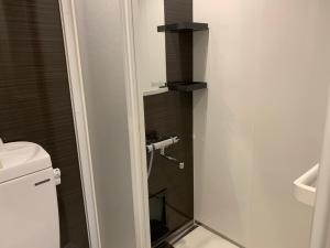 a bathroom with a toilet and a glass shower door at Seaside Hotel The Beach in Chatan