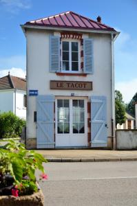 um edifício branco com portas azuis e um telhado vermelho em Le Tacot em Pont-de-Poitte