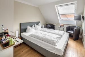 1 Schlafzimmer mit einem Bett mit 2 Stühlen und einem Fenster in der Unterkunft Hotel Zum Roten Tore in Lüneburg