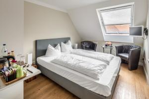 a bedroom with a bed with two chairs and a window at Hotel Zum Roten Tore in Lüneburg