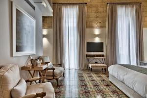 a hotel room with a bed and a couch and a tv at 66 Saint Paul's & Spa in Valletta
