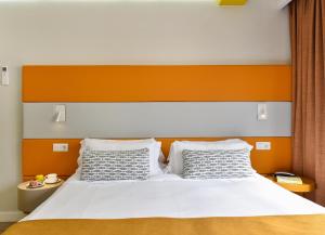a bed with an orange and white headboard and two pillows at Hotel Apartamento Bajamar in Las Palmas de Gran Canaria
