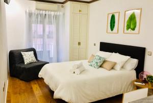 - une chambre avec un grand lit et une chaise dans l'établissement CHUECA Apartamentos, à Madrid