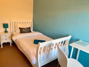 1 dormitorio con cuna blanca y pared azul en Durban House Kettering, en Kettering