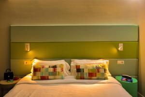 a bed with a green headboard and two pillows at Hotel Apartamento Bajamar in Las Palmas de Gran Canaria