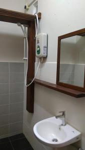ein Badezimmer mit einem weißen Waschbecken und einem Spiegel in der Unterkunft Naura Roomstay in Kuala Tahan